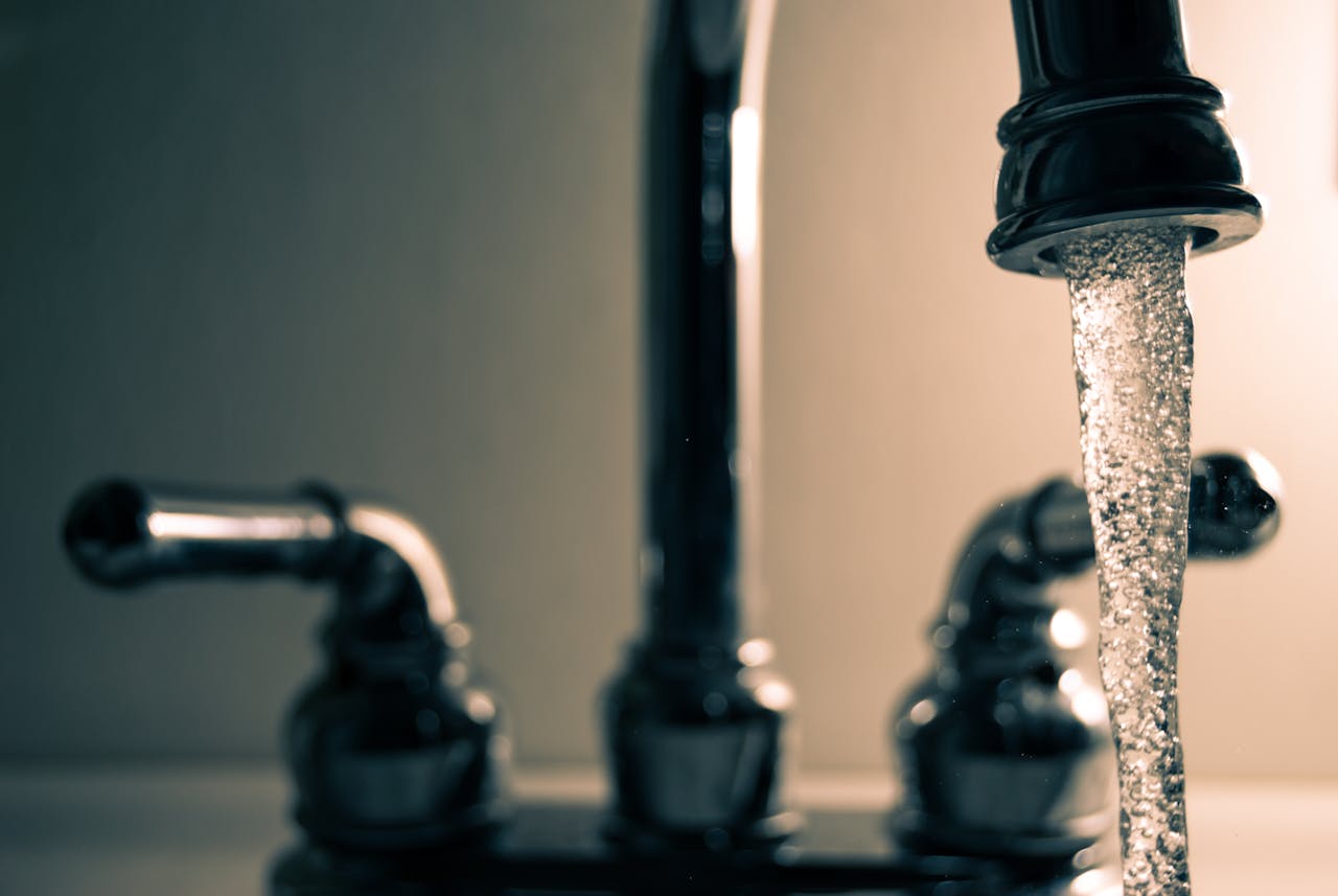 hero-about A detailed shot of water flowing from a steel faucet, ideal for themes on cleanliness or plumbing.